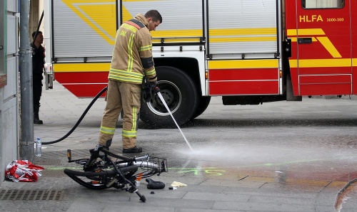 Hasič čistí ulicu od krvi pri zničenom bicykli na mieste nehody, kde vodič terénneho vozidla vrazil do davu ľudí v centre Grazu na juhu Rakúska.