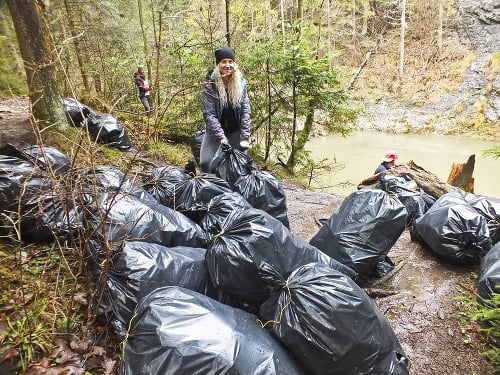 Dobrovoľníčka Veronika Lisoňová vypomáha pri vynášaní vriec s odpadom na brehu Hornádu.