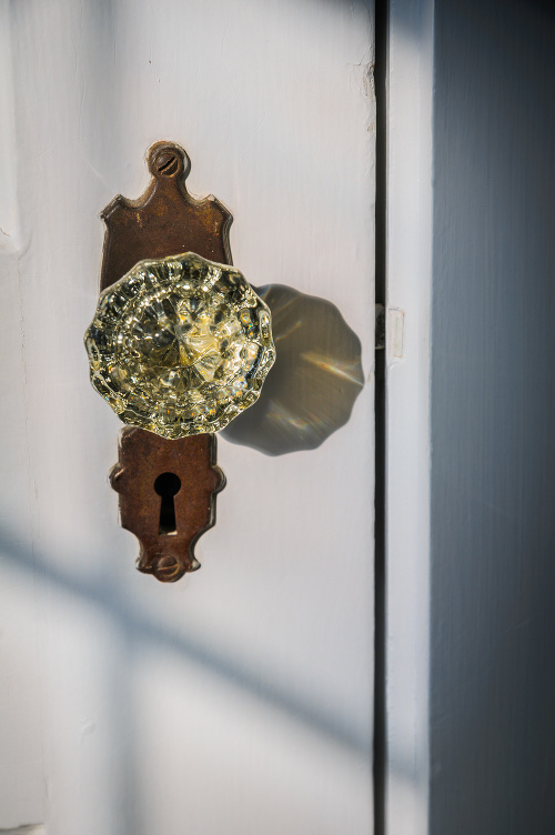 Detail and light refraction of an old fashioned glass doorknob on a  brass escutcheon with a key hole.