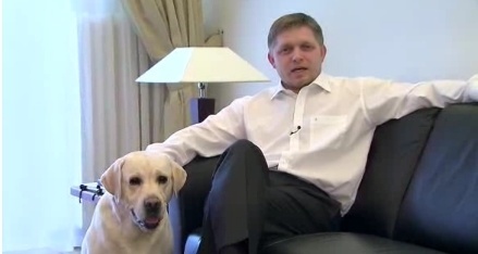 Robert Fico v ležérnej póze na pohovke hladká psa Larryho. 