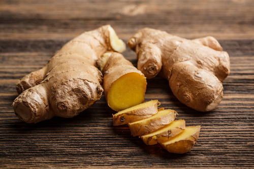 Fresh ginger, whole and sliced on rustic wooden background