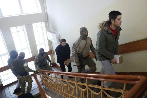 Príslušník ruskej Federálnej bezpečnostnej služby (FSB) eskortuje ukrajinských námorníkov na súdne pojednávanie v Moskve.