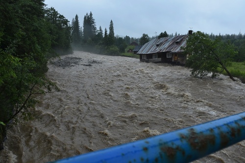 Rozvodnený potok Javorinka, ktorý berie so sebou starší dom v Podspádoch vo Vysokých Tatrách.
