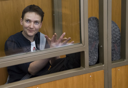 Ukrajinská pilotka Nadija Savčenková sa usmieva a tlieska v presklenej klietke v súdnej sieni počas súdneho procesu v Donecku 22. marca 2016.