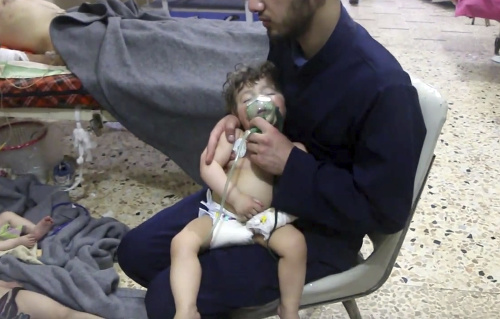 Na snímke zverejnenej Sýrskou civilnou obrannou skupinou Biele helmy, zdravotník dáva kyslíkovú masku dieťaťu po údajnom chemickom útoku v sýrskom meste Dúmá.