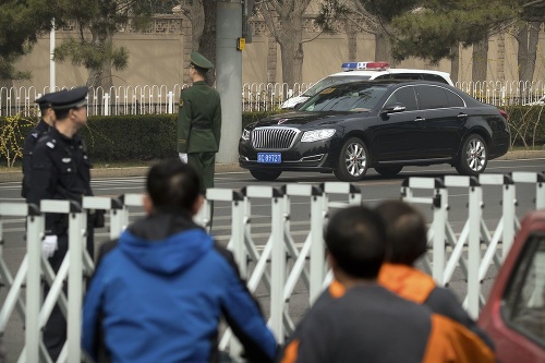 Policajti a bezpečnostní pracovníci hliadkujú na ceste v Pekingu.