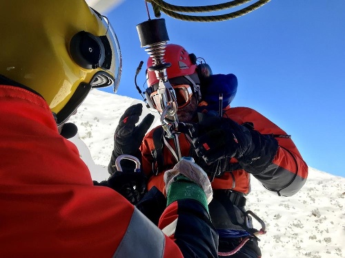 K ťažko zranenej freeridistke sa z vrtuľníka spustil horský záchranár. 
