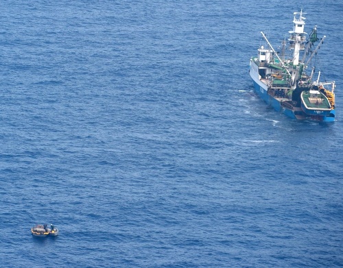  Drevená záchranna loďka (vľavo) preváža sedem preživších z nezvestného trajektu.