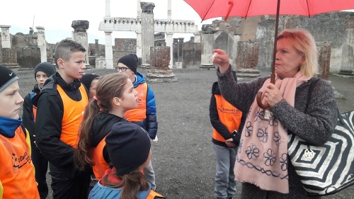 Deti počúvajú výklad počas exkurzie v Pompejach.