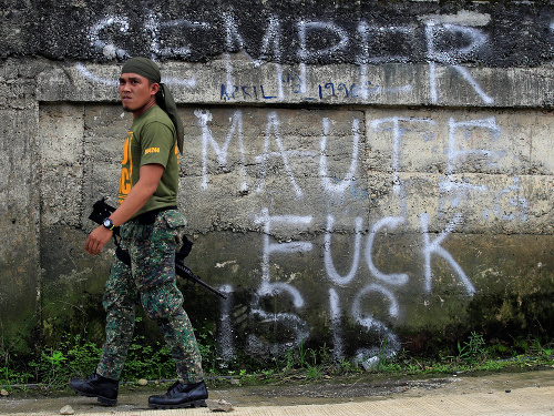Vojak v meste Marawi, za ním grafit proti Islamskému štátu.