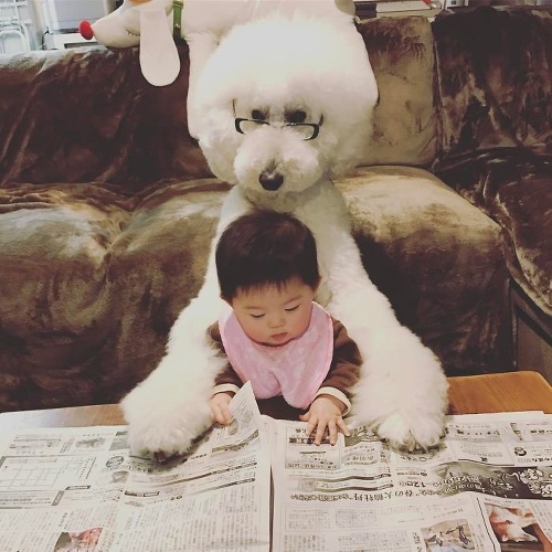 Dievčatko si so štvornohým  kamarátom  prezerá  noviny.