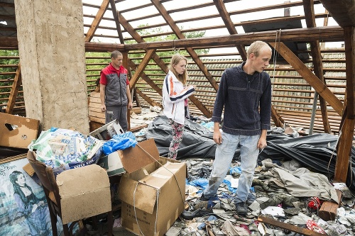 Na snímke zľava István Nagy, Csilla Oroszová a Aron István Nagy si prezerajú zničenú strechu domu po silnom krupobytí v dedine Rozsály.