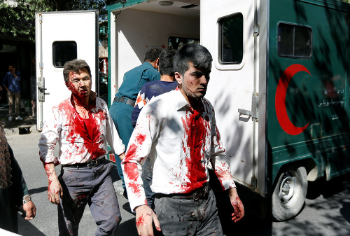 Muži pokrytí krvou po výbuchu v Kábule.