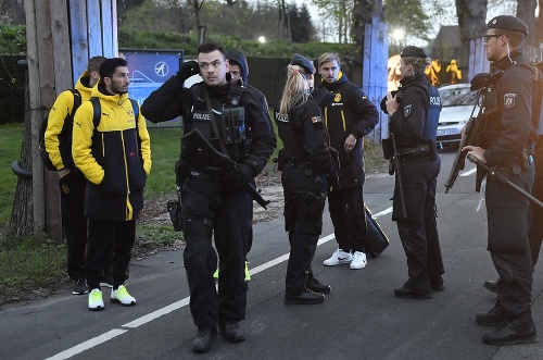 Na snímke hráč Dortmundu Marcel Schmelzer sa rozpráva s príslušníkmi polície  neďaleko poškodeného autobusu po bombovom útoku v Dortmunde 