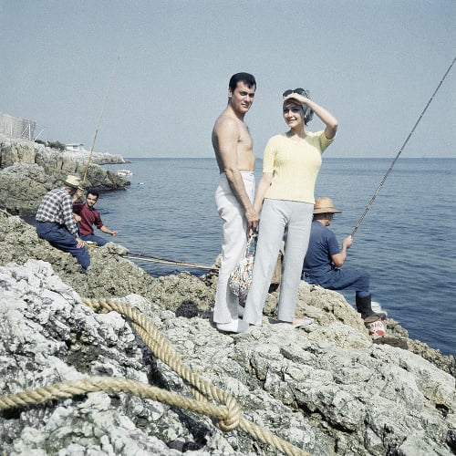 Na archívnej snímke z roku 1965 americký herec Tony Curtis a jeho manželka Christine Kaufmannová sa držia za ruky na skale na pláži v Cannes.