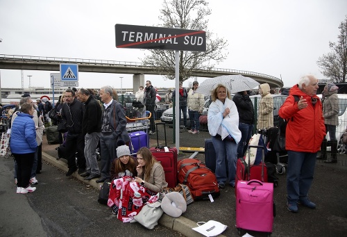 Cestujúci čakajú po streľbe na francúzskom letisku vonku.