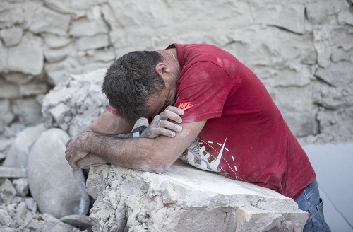 Bezradný muž plače na sutinách domu v meste Amatrice po otrasoch v strednom Taliansku.