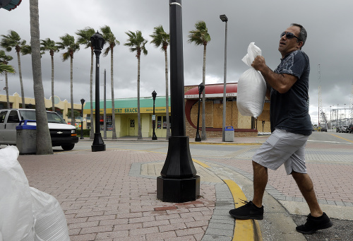 Muž nesie vrecia s pieskom k svojmu obchodu pred príchodom hurikánu Matthew v Daytona Beach na Floride.