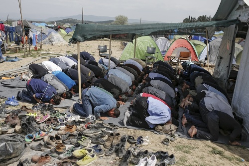 Migranti počas modlitby v utečeneckom tábore na grécko-macedónskych hraniciach pri Idomeni.