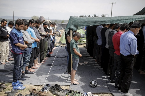 Migranti počas modlitby v utečeneckom tábore na grécko-macedónskych hraniciach pri Idomeni.