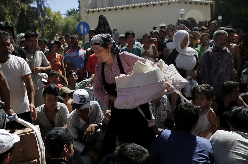Migranti čakajúci na registráciu na gréckom ostrove Kos, v popredí žena s bábätkom.
