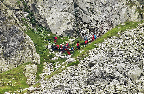 Záchranári znášajú nehybné telo do doliny.