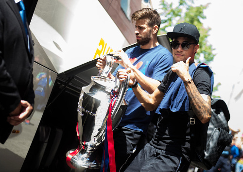  Futbalisti Barcelony Gerard Pique (vľavo) a Neymar odchádzajú s trofejou z hotela po triumfe vo finále Ligy majstrov v Berlíne.