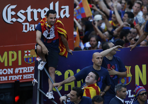 Futbalista Barcelony Xavi Hernandez (vľavo) jazdí v otvorenom autobuse počas osláv.