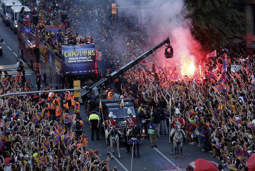  Otvorený autobus s futbalistami Barcelony prechádza okolo horiacej svetlice počas osláv triumfu katalánskeho veľkoklubu. 