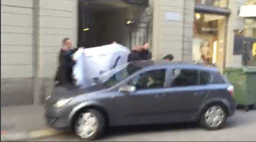 Na  snímke z mobilného telefónu hotoloví zamestnanci zakrývajú bielou plachtou osobu, ktorá vychádza bočným vchodom luxusného hotela Baur au Lac a nastupuje do odstaveného auta vo švajčiarskom meste Zürich.