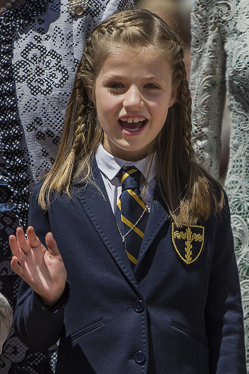 Deväťročná korunná princezná Leonor oblečená v školskej uniforme máva počas svojho prvého prijímania.