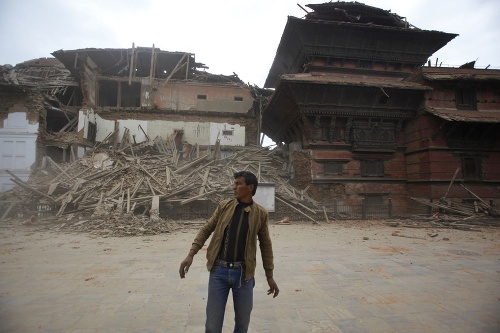Muž stojí pred troskami budov na námestí Durbar v  Káthmandu v Nepále.