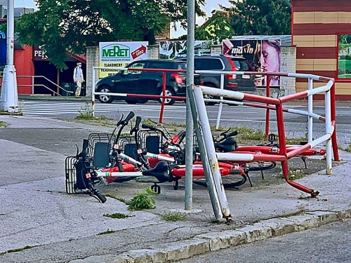 Zdieľané bicykle sú pohodené pri chodníkoch a v tráve. 