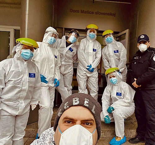 Folkloristi pred prvou vlnou pandémie na schodoch do Domu Matice slovenskej a v ochranných odevoch.