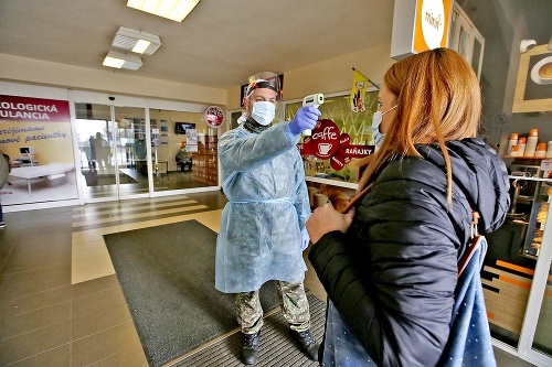 Vojaci merajú pri vstupe do nemocnice teplotu a zapisujú údaje o pacientoch.