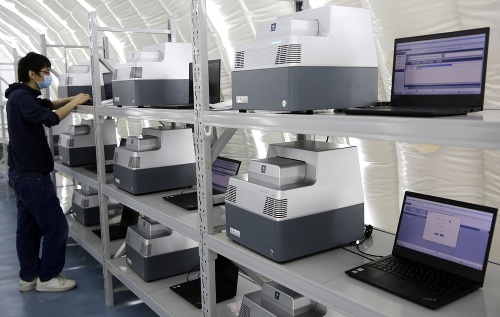 Technik dáva do prevádzky testovacie prístroje v dočasnom laboratóriu na vyhodnocovanie testov na ochorenie COVID-19.