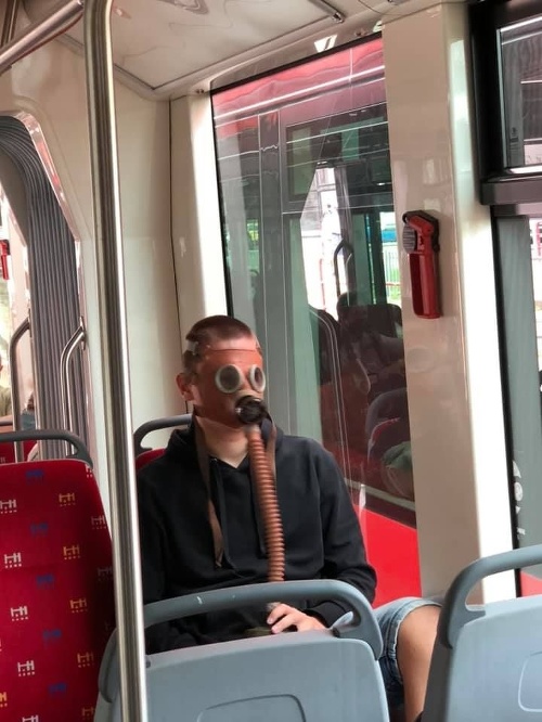 Muž sa viezol električkou s plynovou maskou na tvári.