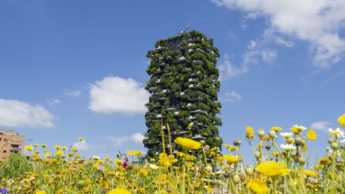 Milano, Italy. Bosco Verticale, view at the modern and ecological skyscraper with many trees on each balcony. Public park in the foreground with fresh and colored flowers