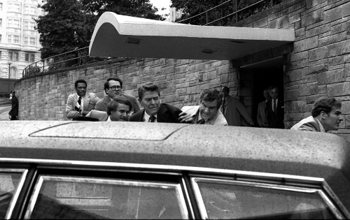 Na archívnej snímke z 30. marca 1981 americký prezident Ronald Reagan (uprostred), ktorému tajní agenti pomáhajú do limuzíny po tom, čo bol postrelený pred hotelom Hilton vo Washingtone.