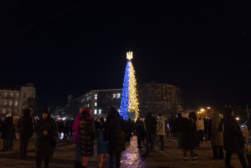 Ľudia počas rozsvietenia vianočného stromčeka vo farbách ukrajinskej národnej zástavy v Kyjeve 19. decembra 2022.