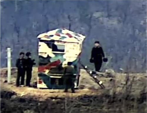 Na nedatovanej snímke juhokórejského ministerstva obrany z 27. novembra 2023, severokórejskí vojaci stavajú drevené strážne stanovište v demilitarizovanej zóne na hraniciach medzi KĽDR a Južnou Kóreou. 
