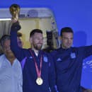 Argentínsky futbalista Messi drží trofej pre víťaza MS vo futbale, vpravo je tréner Lionel Scaloni.