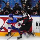 Slovenský hokejista Juraj Slafkovský (vľavo) a hráč Kanady Dylan Cozens bojujú o puk pri mantineli.