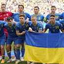 Ukrajinskí futbalisti zo základnej jedenástky pózujú s národnou vlajkou pred zápasom základnej E-skupiny Rumunsko - Ukrajina na ME vo futbale v Mníchove