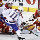 Christian Dvorak (28) a Brendan Gallagher (11) z Montreal Canadiens sledujú hru, zatiaľ čo brankár Calgary Flames Dustin Wolf (vpravo) bráni svoju bránku