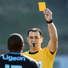 Rozhodca ukazuje hráčovi žltú kartu.