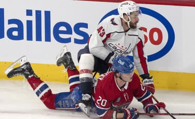 Slovenský hokejista v drese Montrealu Canadiens Juraj Slafkovský (dole) a hráč Washingtonu CapitalsTom Wilson bojujú o puk.