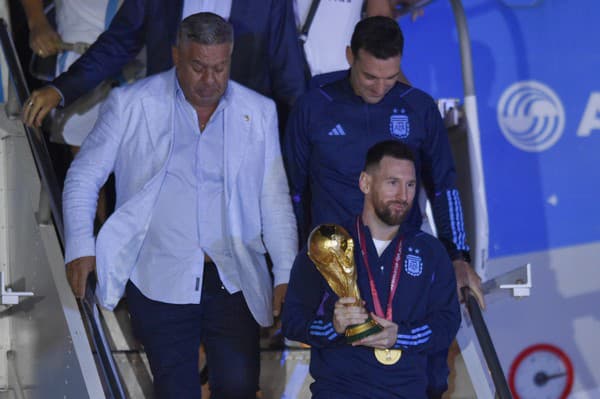 Argentínsky futbalista Lionel Messi drží trofej pre víťaza MS vo futbale počas vystupovania z lietadla v Buenos Aires.