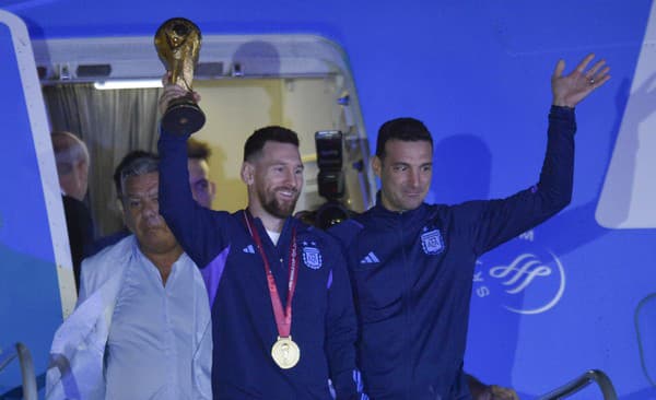 Argentínsky futbalista Messi drží trofej pre víťaza MS vo futbale, vpravo je tréner Lionel Scaloni.