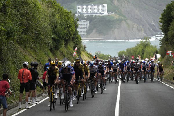 Skupina cyklistov šliape do pedálov počas prvej etapy cyklistických pretekov Tour de France.